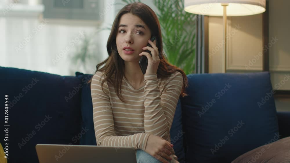 Attractive young woman is speaking on smartphone with client from home Attractive young woman is speaking on smartphone with client from home