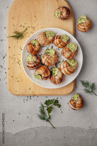 Burgundy escargots with green oil and parsley on a light board