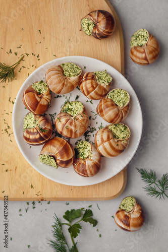 Burgundy escargots with green oil and parsley on a light board