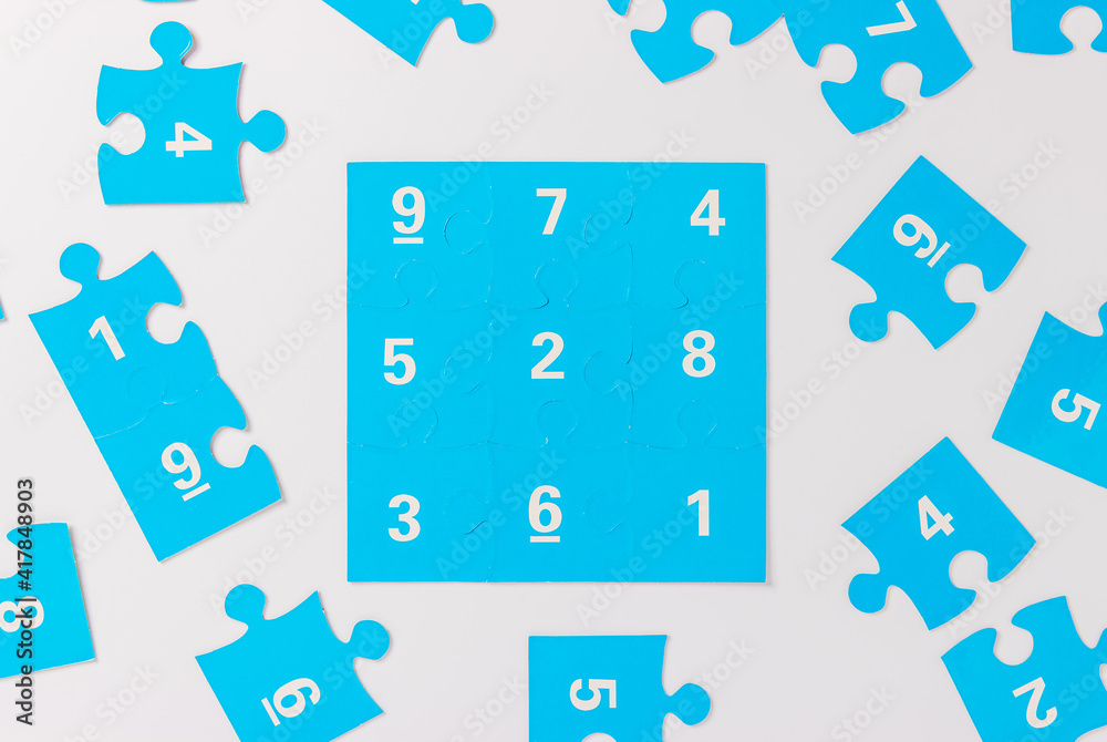 Naklejka premium Blue puzzle pieces with numbers on a white background, logo of autism. April 2, Autism World Awareness day. Top view
