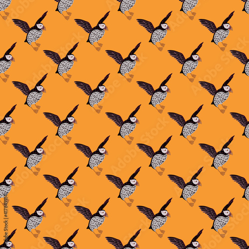 Bright animal iceland seamless pattern with grey and black colored puffin ornament. Orange background.
