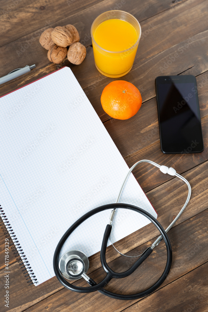 Top view of a doctor's work desk. Notebook, stethoscope and mobile phone on dark wood background. Top view of a doctor's work desk. Notebook, stethoscope and mobile phone on dark wood background.