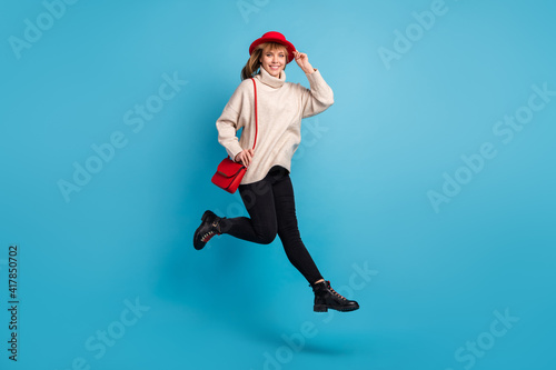 Full length body size photo model in red hat jumping high stepping forward isolated bright blue color background