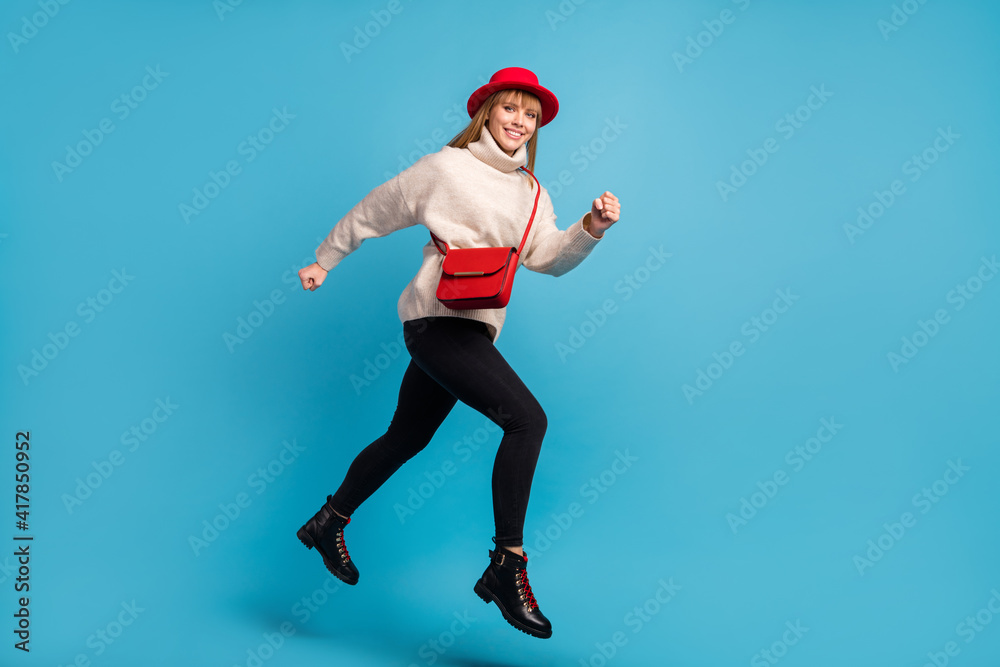 Full length body size photo model in red hat jumping high running fast smiling isolated vivid blue color background