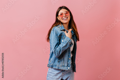 Refined brunette girl in jeans looking at camera. Studio shot of good-humoured woman wears denim jacket. © Look!