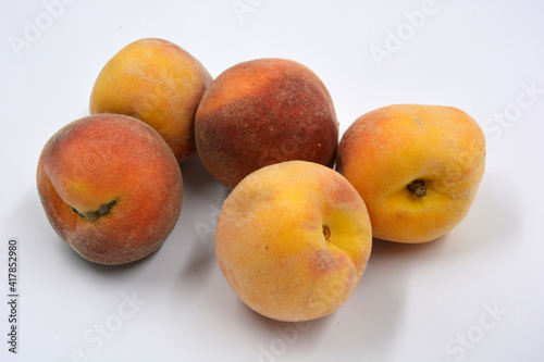 Tasty and useful fresh fruits, ripe red and orange peaches with a terry white skurt are located on a white background. 