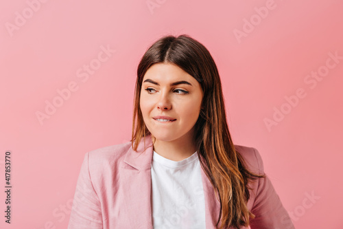 Sensual brunette girl looking away. Beautiful young woman with straight hair standing on pink background.