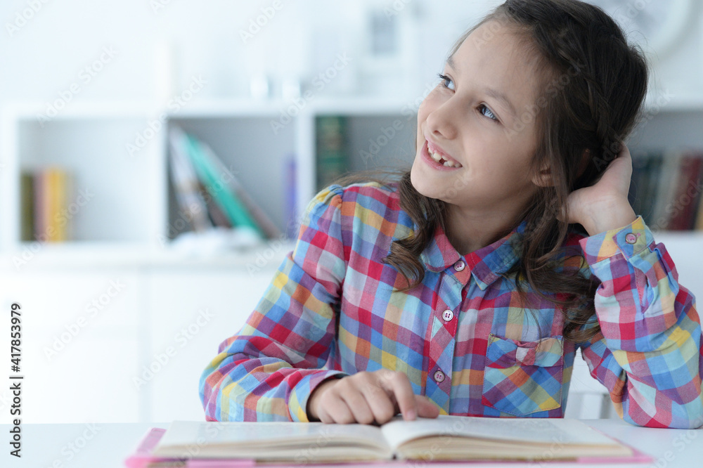 Cute schoolgirl sitting at table at home Cute schoolgirl sitting at table at home