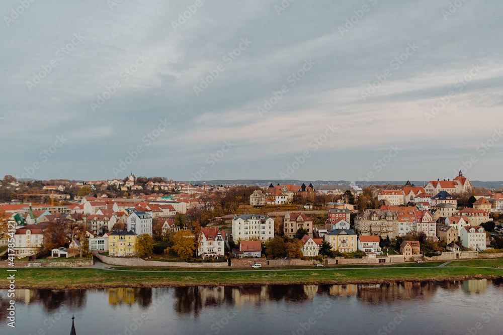 Fototapeta premium The red tile roofs of old European city Meissen on the embankment of river Elba