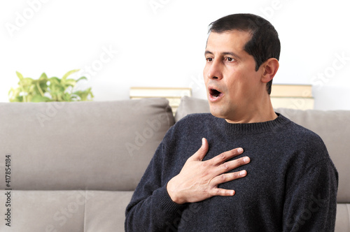 Man suffering respiration problems sitting on a couch in the living room at home