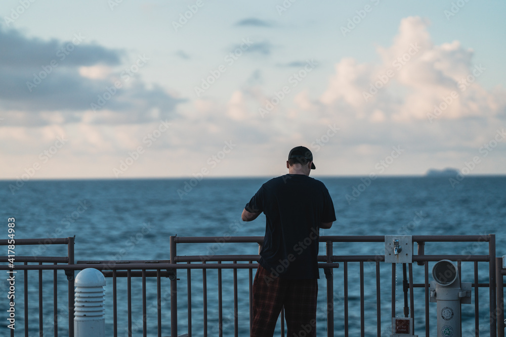 Fototapeta premium man looking at the sea fisherman sky clouds blue cap