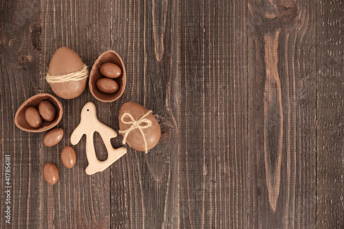 Flat lay of decorated chocolate eggs, candies and bunny on the wooden background. Handmade easter decoration. Copy space, place for text. Eater gift.