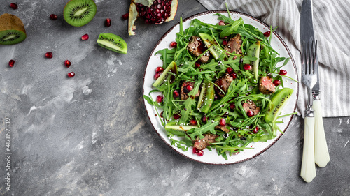 Salad with chicken liver. Fresh vegetable salad. Meat salad with liver, kiwi and pomegranate and fresh arugula. banner, menu recipe place for text, top view