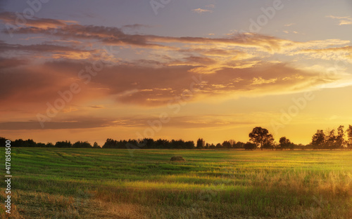 Beautiful sunset with dramatic sky over agricultural field.