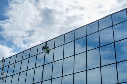 Window Washer Harness on Side of Building with Clouds and Reflections on Windows