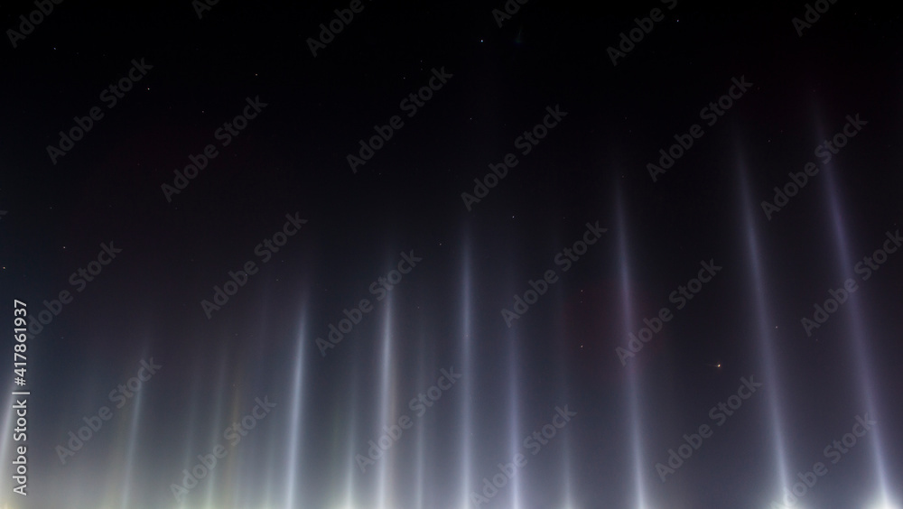 Light poles from the spotlights, imitation of the Northern Lights. Winter pillars in severe frost.