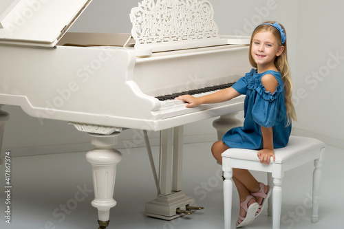 Charming girl posing at grand piano