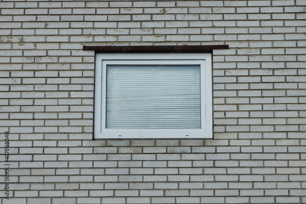 one white square window on a gray brick wall of a building one white square window on a gray brick wall of a building