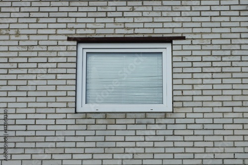 one white square window on a gray brick wall of a building