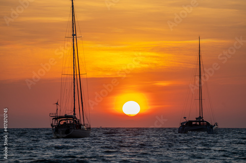 A yacht in the sea with a big sunset