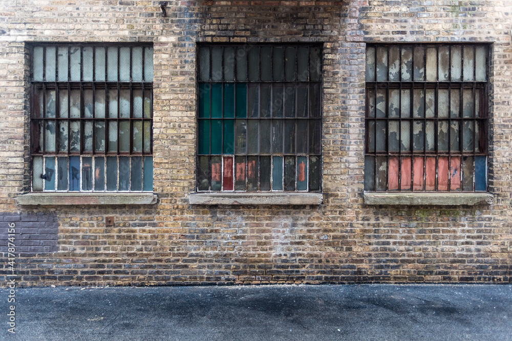 Three windows on back of vintage industrial brick warehouse building on wet day in urban Chicago