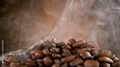 Falling Roasted Coffee Beans on Brown Background, close-up.