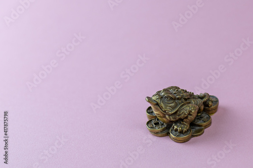 Feng Shui money mascot - Chang Chu - bronze figure of a frog sitting on coins, isolated on a pink background place for text background image