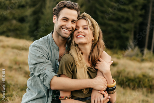 Loving young couple hugging and smiling together on nature background © Александр Шуневич
