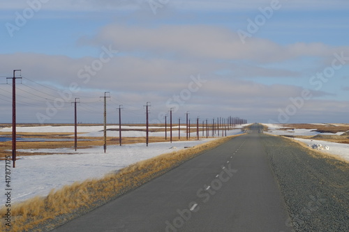 Beautiful spring road and white clouds in the arctic tundra