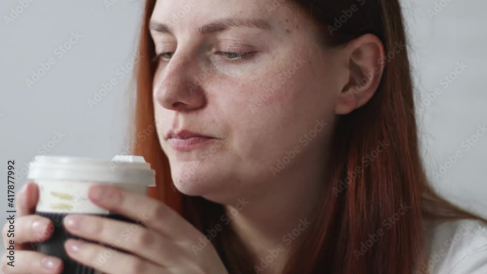 Young Caucasian girl with long hair drinking hot latte coffee from paper cup enjoying morning breakfast Young Caucasian girl with long hair drinking hot latte coffee from paper cup enjoying morning breakfast