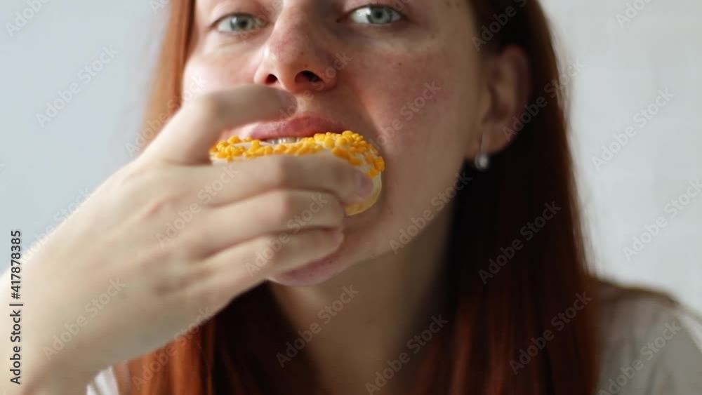 Close up portrait of Caucasian young pretty woman bites tasty doughnut with mango filling, enjoying Close up portrait of Caucasian young pretty woman bites tasty doughnut with mango filling, enjoying
