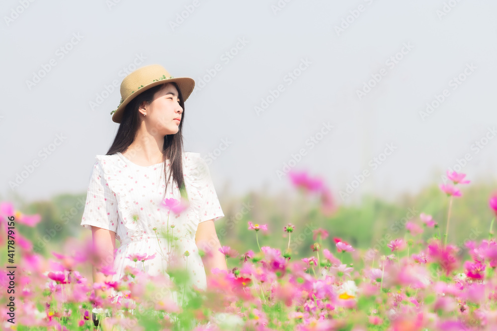 Asian woman with white dress relaxing on Margaret Aster flower field in garden 