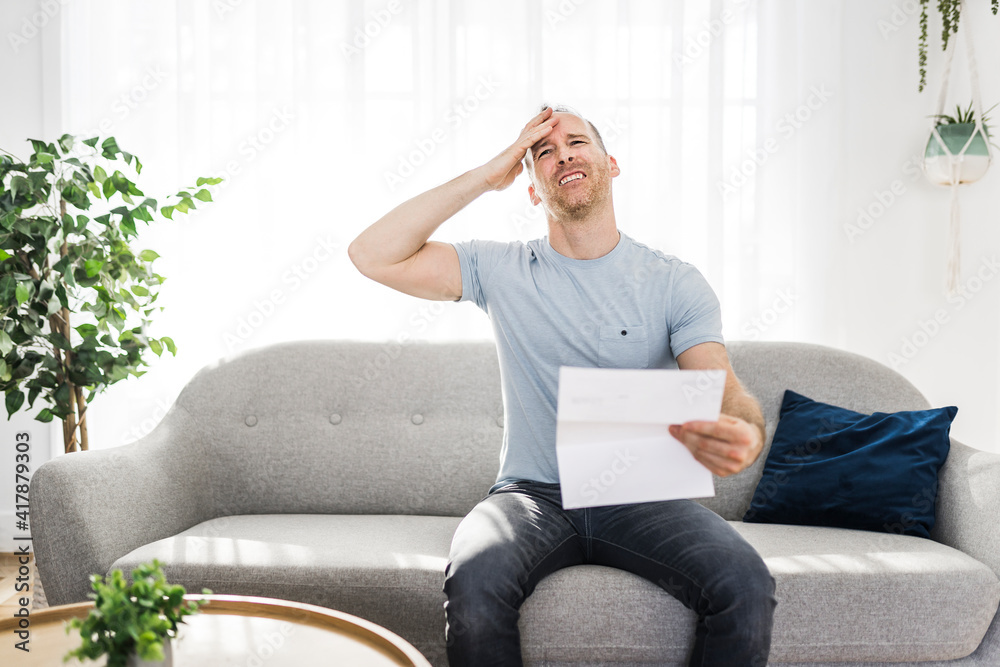 Obraz premium Shocked man holding some documents on sofa livingroom