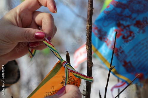 Woman Hands Binds Prayer Flag on Bare Tree Branch