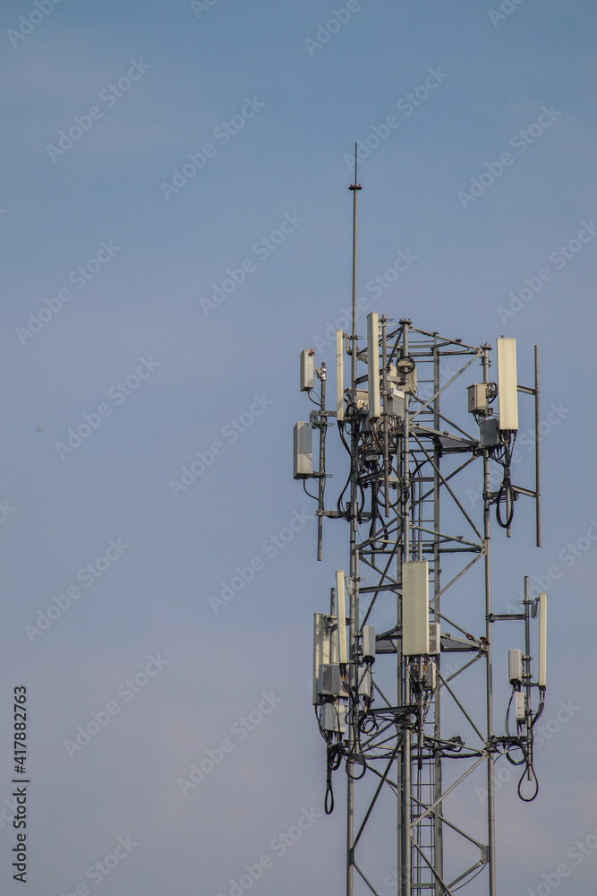 5G telecommunication tower 5G mobile phone wireless antenna machine Located in the center of the city against a blue sky background. 5G telecommunication tower 5G mobile phone wireless antenna machine Located in the center of the city against a blue sky background.