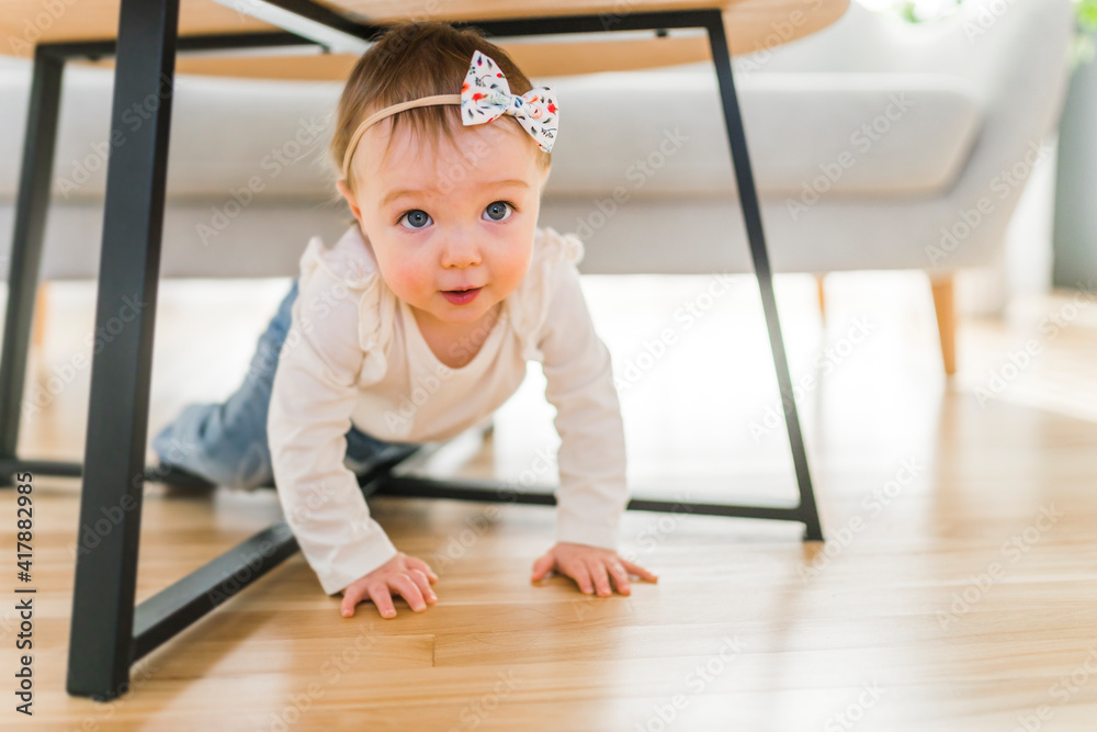 Portrait of a baby girl having fun underneath the table in the living room Portrait of a baby girl having fun underneath the table in the living room