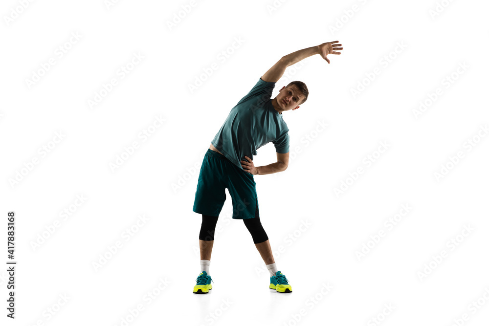 Stretching. Young caucasian male model in action, motion isolated on white background with copyspace. Concept of sport, movement, energy and dynamic, healthy lifestyle. Training, practicing. Authentic