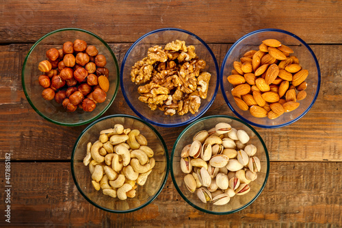 Assorted nuts in a glass bowl on a wooden table.