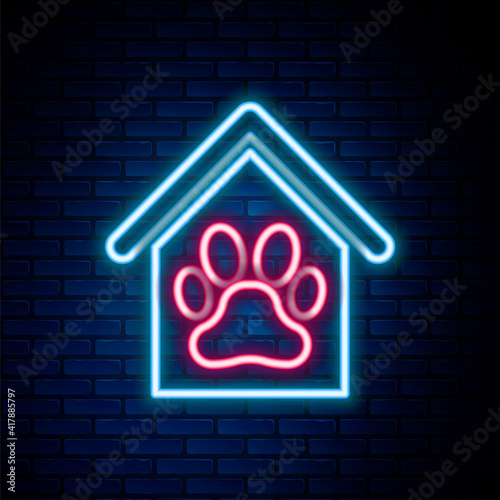 Glowing neon line Dog house and paw print pet icon isolated on brick wall background. Dog kennel. Colorful outline concept. Vector.