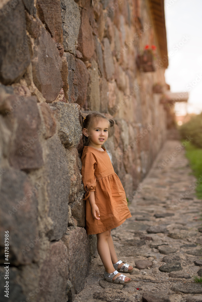 The girl stands at the ancient stone wall. 