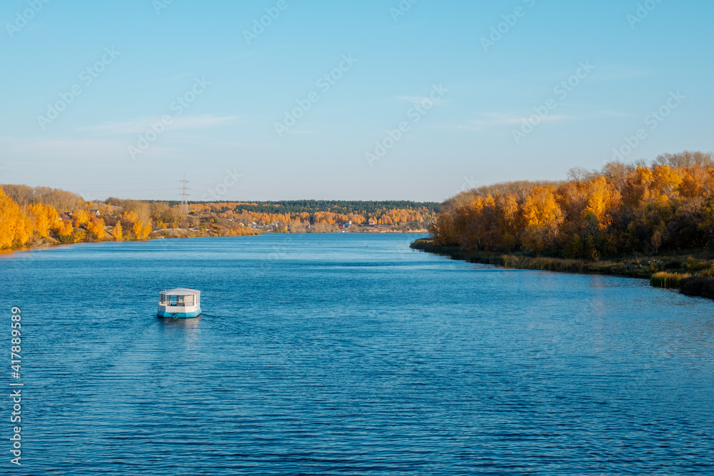 a pleasure boat floats on the river in autumn