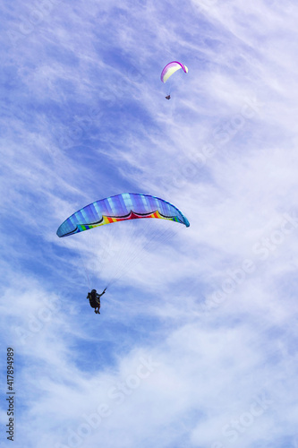 Athlete paragliding against the background of blue sky and clouds on a summer day.