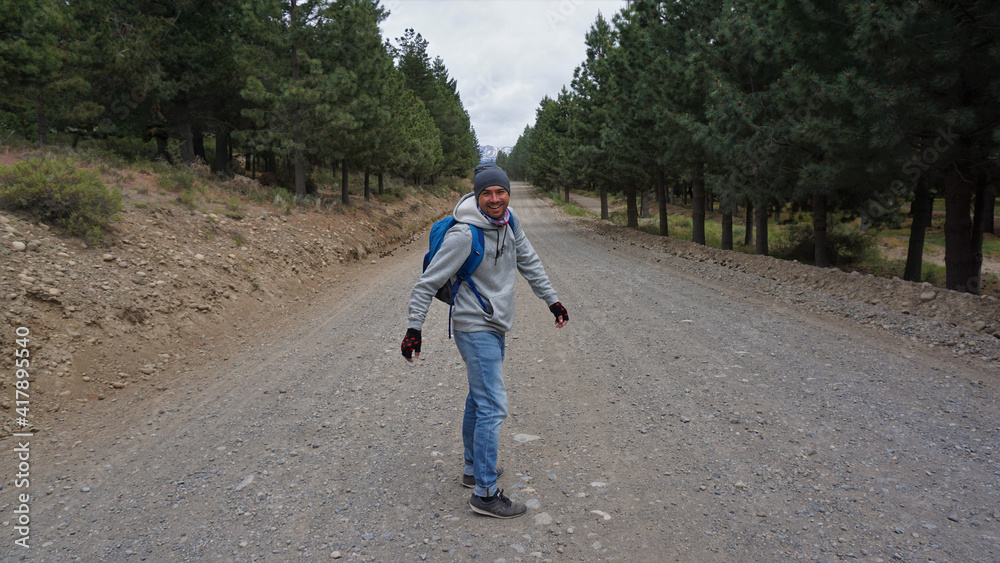 Hombre sonriendo sobre un camino de tierra con arboles Hombre sonriendo sobre un camino de tierra con arboles