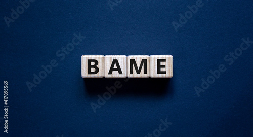 BAME symbol. Abbreviation BAME, black, asian and minority ethnic on wooden cubes. Beautiful grey background. Copy space. Business and BAME, black, asian and minority ethnic concept. photo