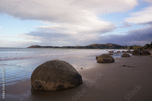 The Moeraki Boulders are unique large round stones lying along of Koekohe Beach in New Zealand