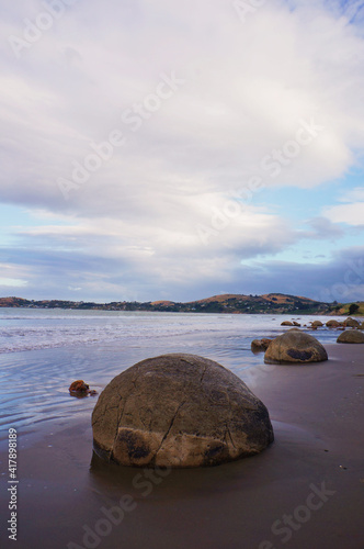 The Moeraki Boulders are unique large round stones lying along of Koekohe Beach in New Zealand