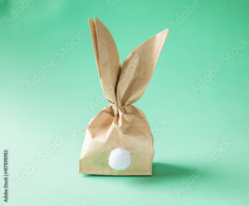 Easter bunny paper gift egg wrapping DIY idea on colorful background. Minimal easter concept, flat lay, copy space