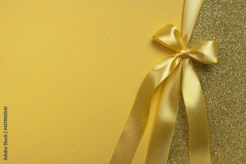 Golden gift shiny card, certificate or texture gift box with yellow ribbon bow. Christmas, new year, birthday, anniversary or sale background. Top view, flat lay, copy space, template for design Golden gift shiny card, certificate or texture gift box with yellow ribbon bow. Christmas, new year, birthday, anniversary or sale background. Top view, flat lay, copy space, template for design