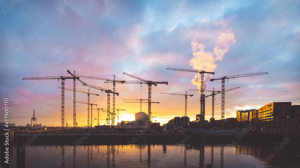 Industrial romantic: Construction field at the port of Hamburg during a sunset. Panorama landscape with cranes. Acknowledging prince: Purple Cranes