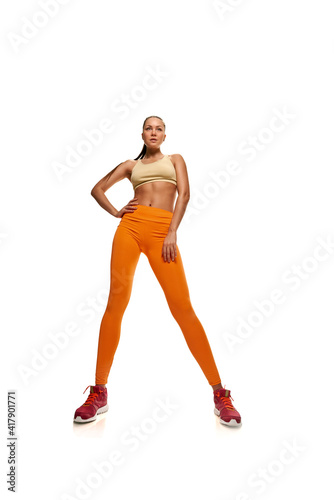 Young sporty woman exercising on white background and stretching legs